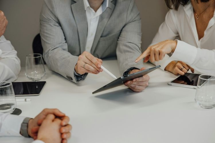 a group of people sitting around a conference table with iPads