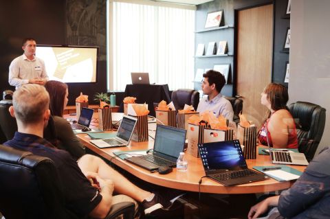 a group of people on laptops around a conference table at a business meeting