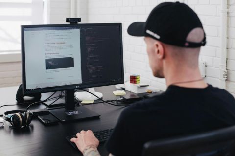 Man at work desk with keyboard looking at computer monitor.