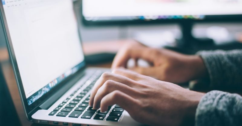 Closeup of a person typing on a laptop keyboard.