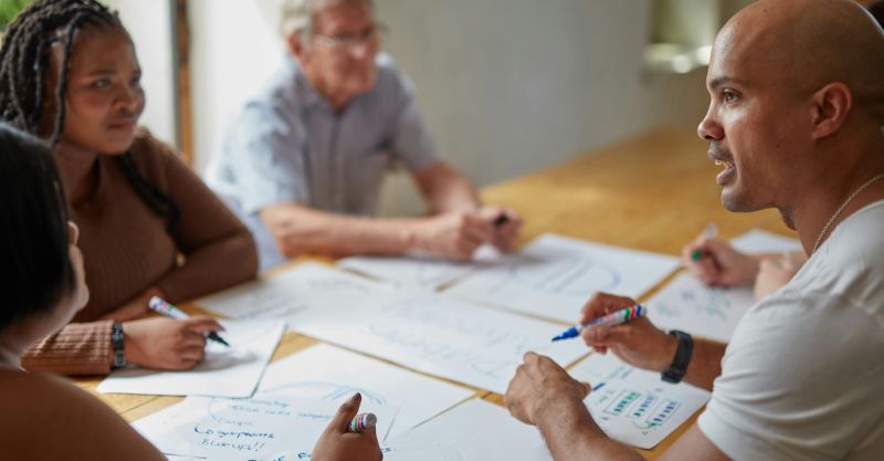 people sitting around a conference table writing on papers