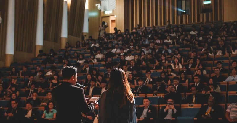 two people giving a presentation on a stage in front of an audience