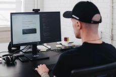 Man at work desk with keyboard looking at computer monitor.
